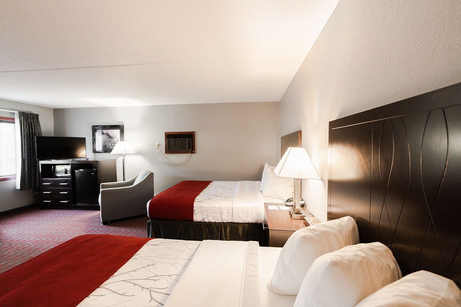 View of the queen beds, seating, dresser and tv in the executive suite