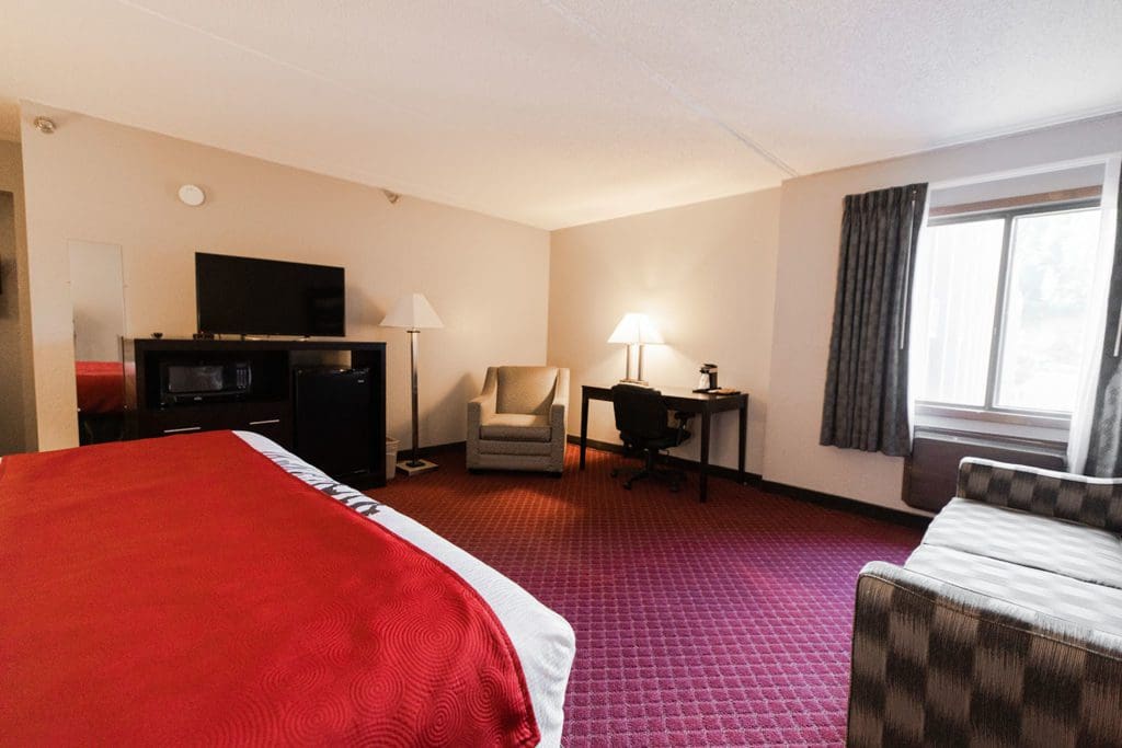 View of the couch, desk, dresser, fridge, microwave and TV in the executive king suite